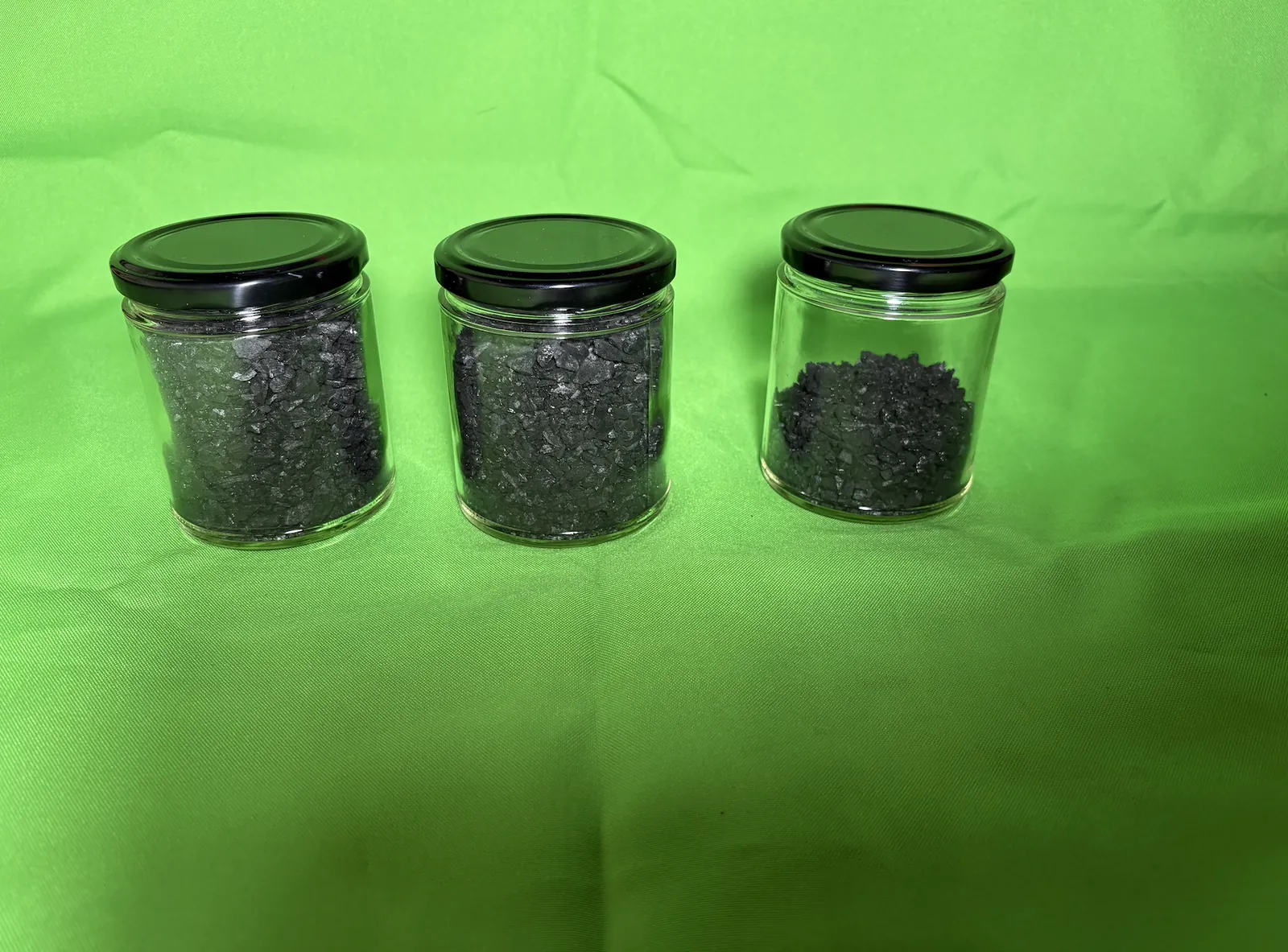Three glass jars holding crushed charcoal