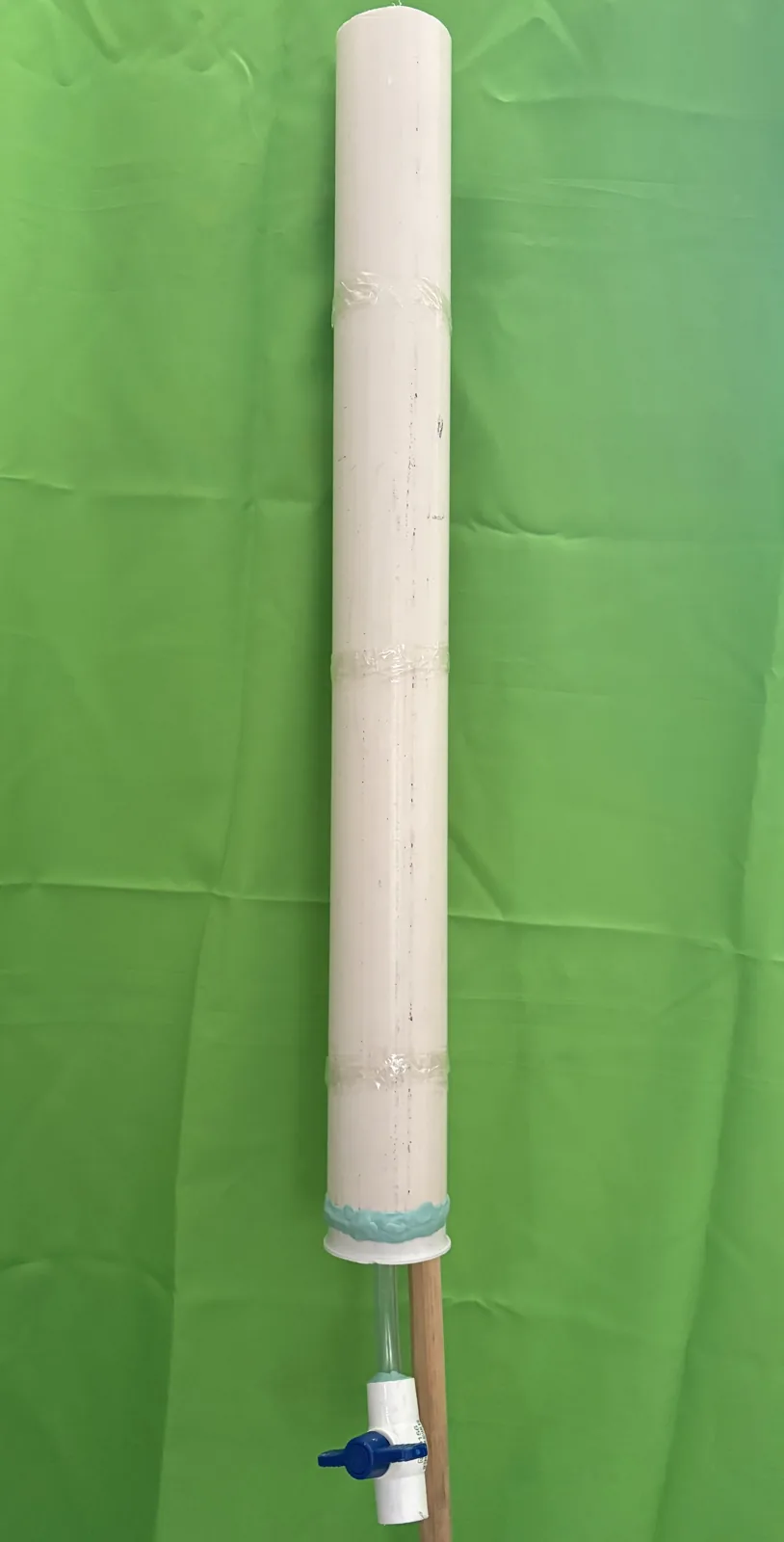 Loaded white PVC column taped to a mop handle, with the ball valve hanging free below